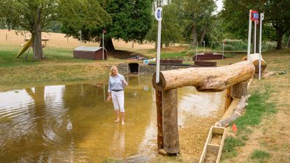 Tina Cook stands barefoot in the Trout Hatchery at Burghley Horse Trials looking at the hanging log jump into the water