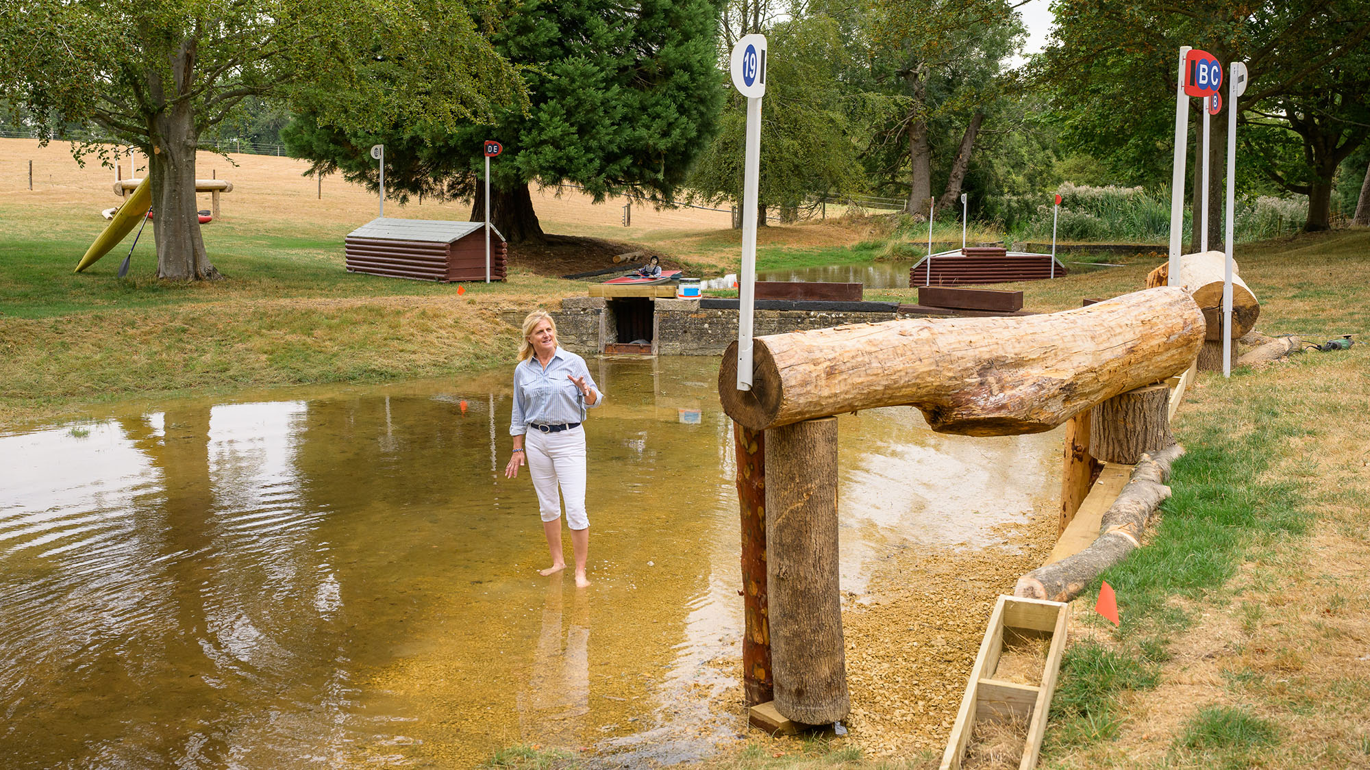 Tina Cook stands barefoot in the Trout Hatchery at Burghley Horse Trials looking at the hanging log jump into the water