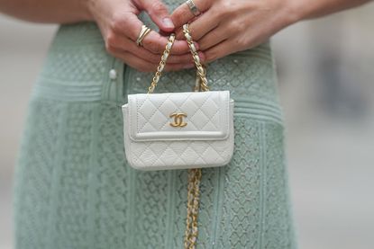 Quilted white leather mini bag with flap closure, gold-tone CC logo, and chain strap by Chanel is seen