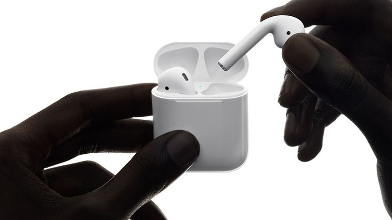 Apple AirPods being taken out of their case by hands that are in shadow