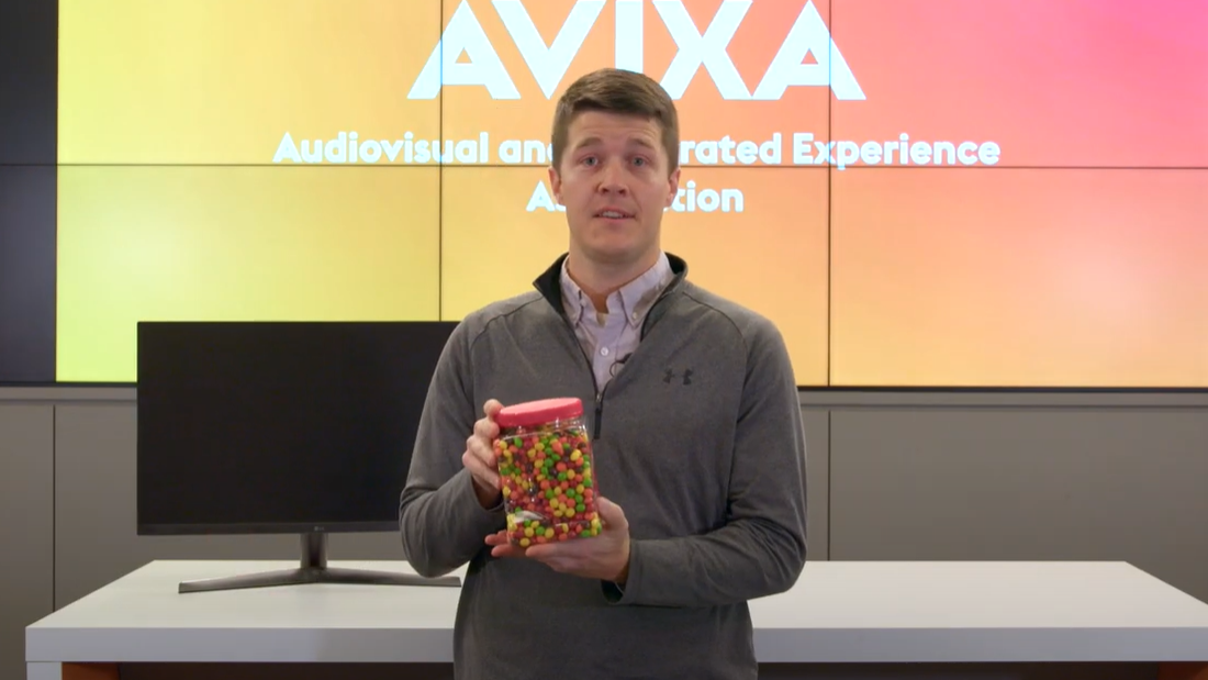 AVIXA&#039;s Mark Metzger stands with a jar of Skittles to explain how pixels work in AVoIP. 