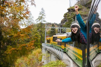 Happy woman traveling by train on a picturesque train road in Swiss