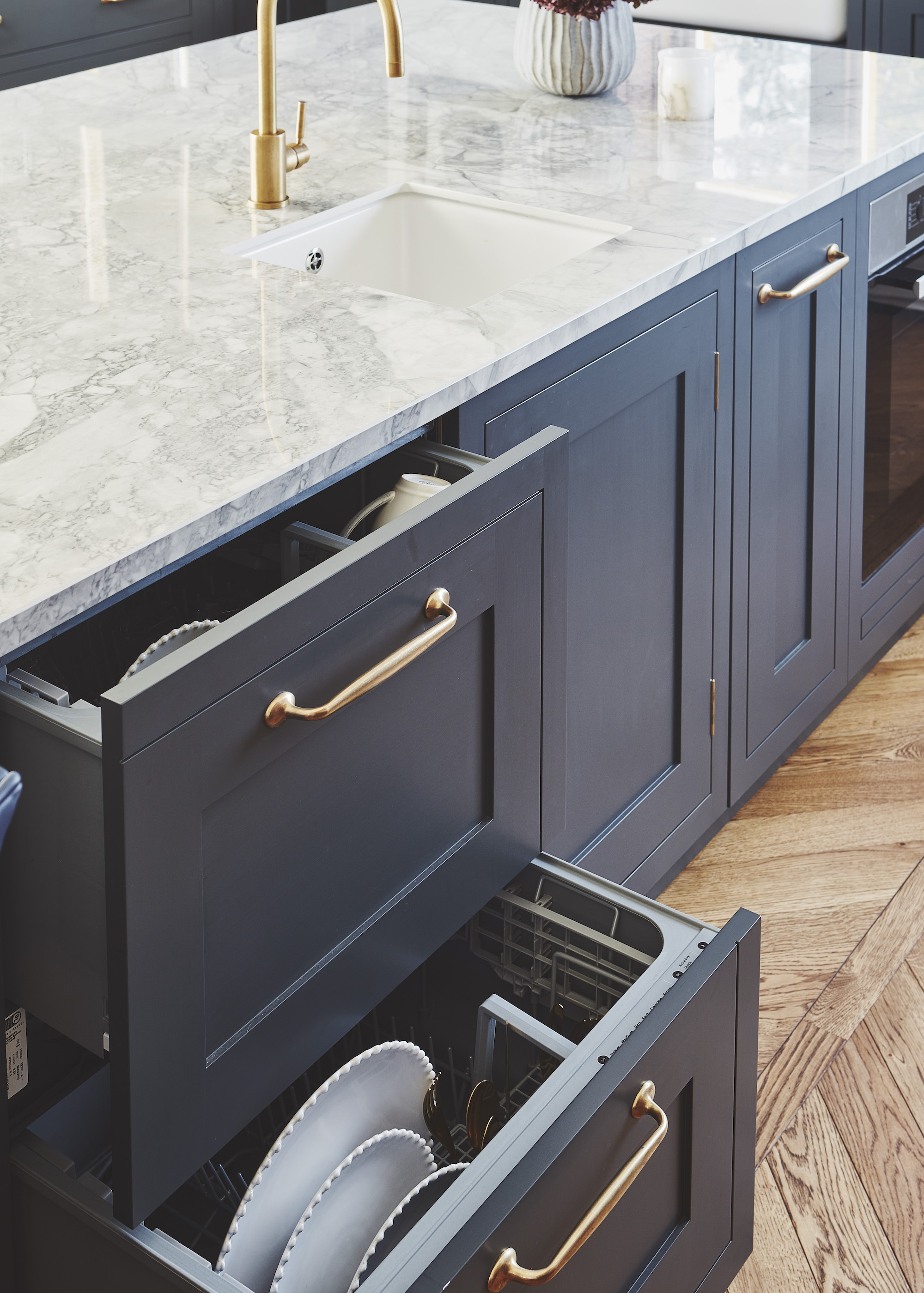 a blue kitchen island with an dishwasher drawers that have plates and cups inside of them
