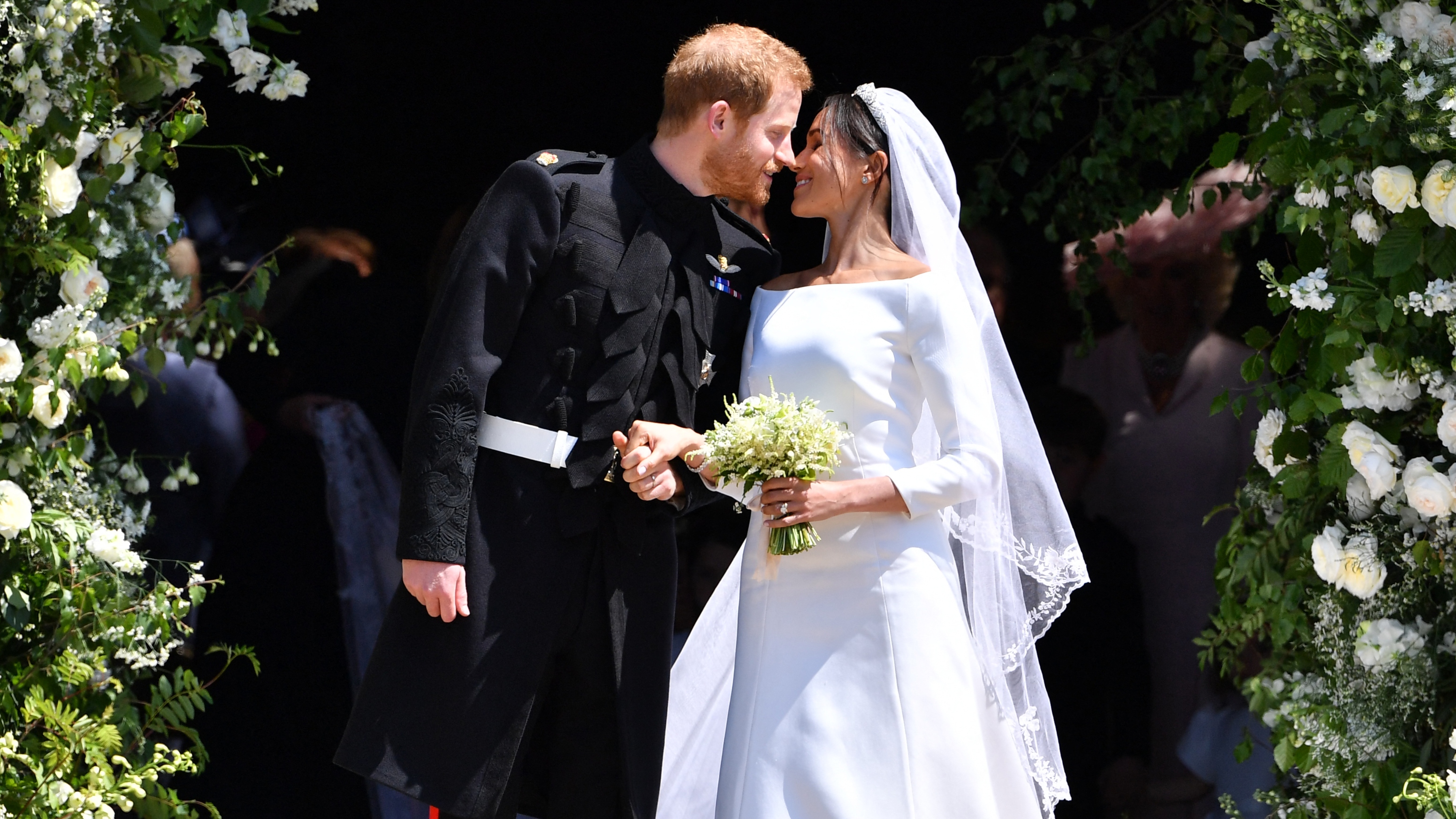 Prince Harry, Duke of Sussex kisses Meghan, Duchess of Sussex as they leave from the West Door of St George&#039;s Chapel, Windsor Castle on their wedding day in 2018