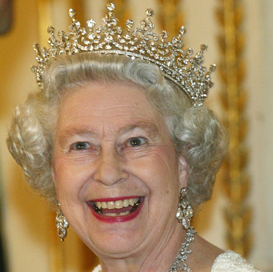 Queen Elizabeth smiling and wearing a diamond tiara and earrings