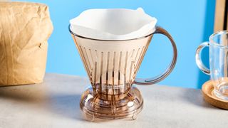 the clever dripper, a brown transparent plastic manual coffee maker with a handle and a sluice feature in the bottom to keep water inside