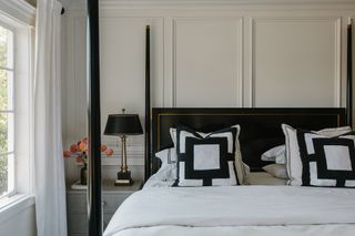 White bedroom with a black four poster bed