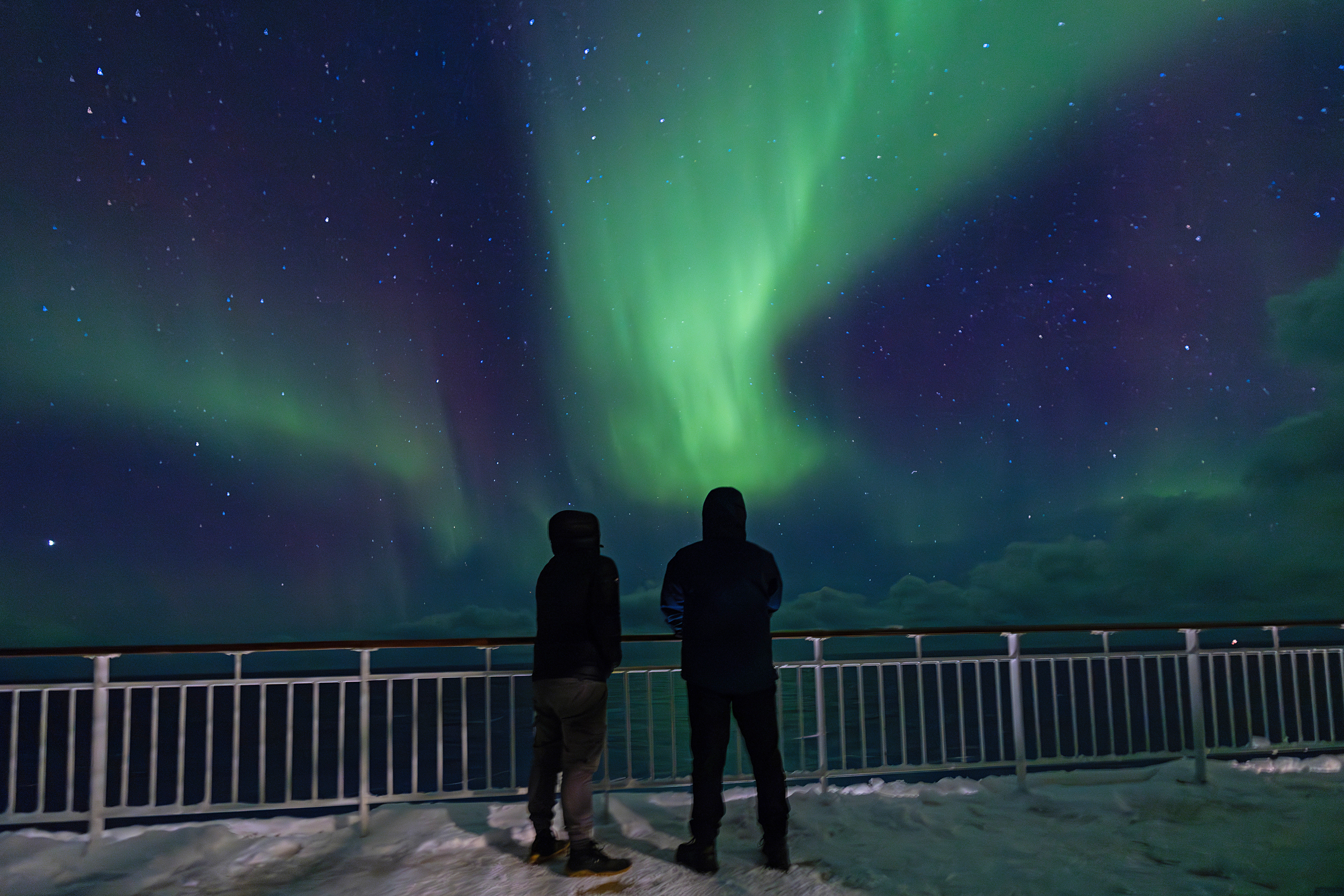 two people watching the northern lights on a cruise ship