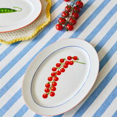 Vintage style tomato serving plate on a blue striped tablecloth.