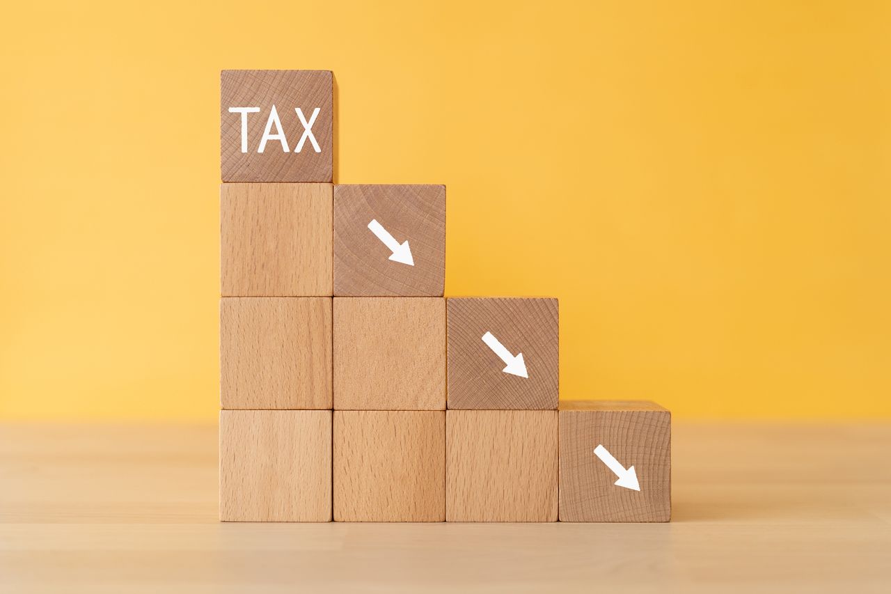 Decreasing tax; Wooden blocks with &quot;TAX&quot; text of concept