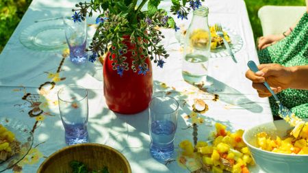 Table with white tablecloth, flowers and food on a spring day