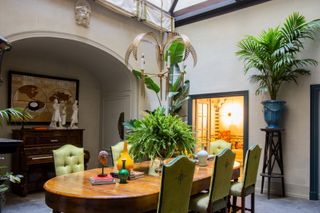 The Glass Yard at The Place Firenze boasts at large wooden table that sits up to eight, the room is adorned with plants and art
