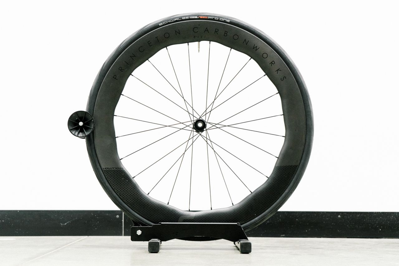 An aero road wheel stands against a white wall