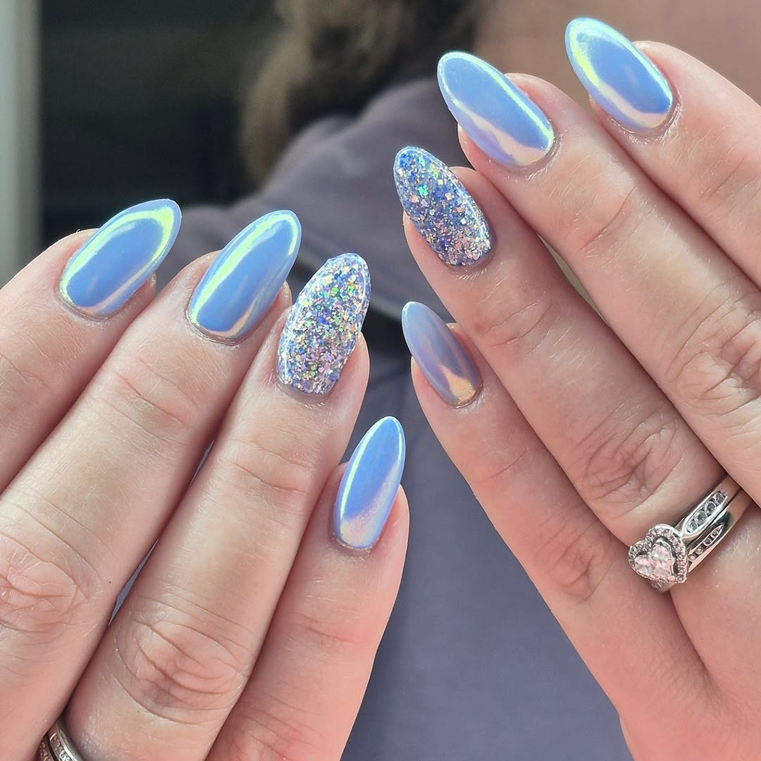 a person wearing light blue chrome nails with glitter