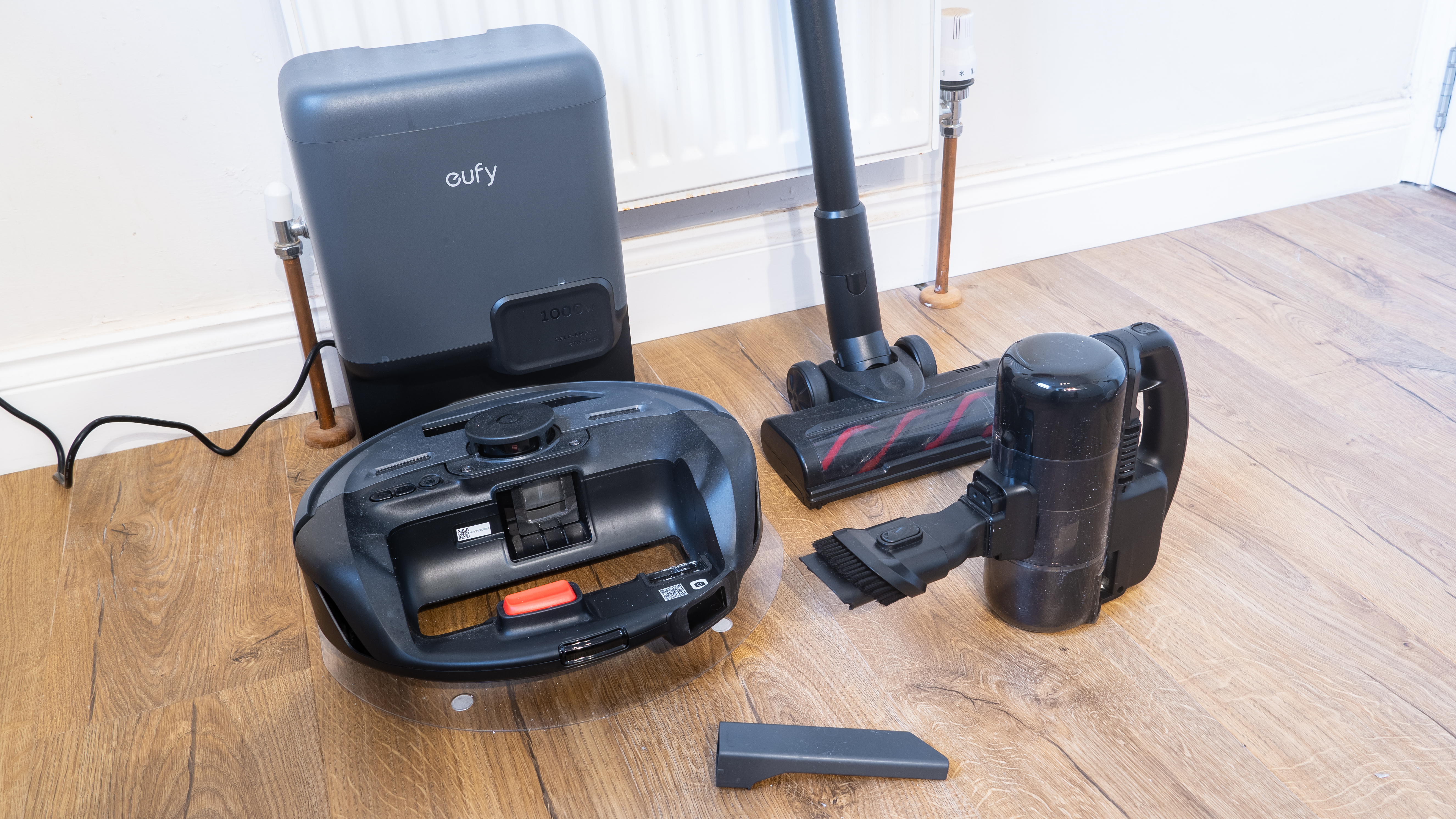 Eufy E20 robovac in dock, with handheld vacuum and other accessories next to it