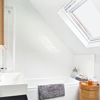 White attic bathroom with skylight and bath