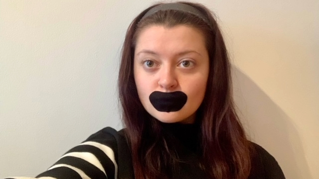 Woman wearing black mouth tape looking at the camera