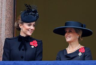 Kate Middleton and Duchess Sophie wearing black coats and hats smiling on Remembrance Day