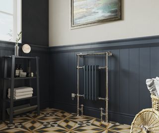 floor mounted radiator with brass frame and dark grey radiator section against dark blue wall
