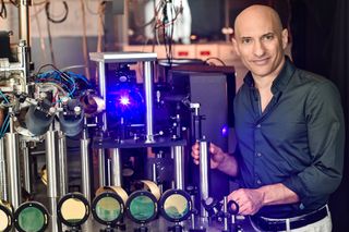 Jeff Steinhauer stands with a machine capable of simulating black-hole conditions in the laboratory.