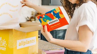 Woman looking at label on a box from Allplants