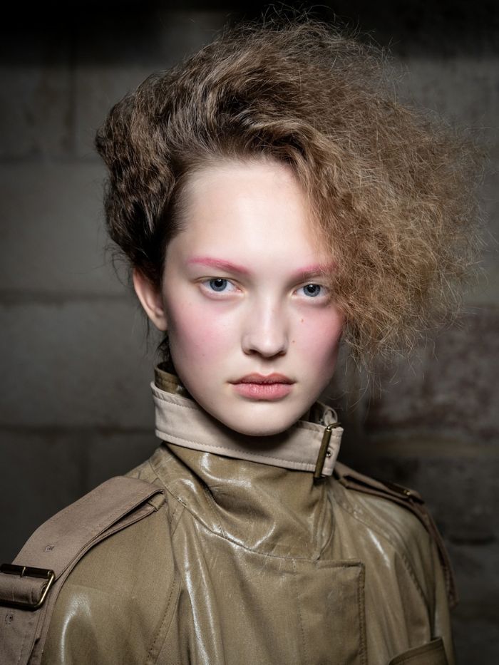 A shot of a model backstage at the S/S 27 Acne Studios show with pink eyebrows