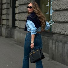 @oliviafaeh wears a blue shirt, blue jeans and carries a black top-handle bag
