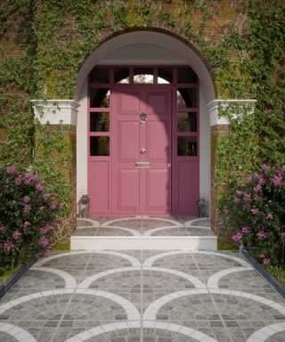 An example of front garden ideas showing a gray tiled path leading up to a pink front door