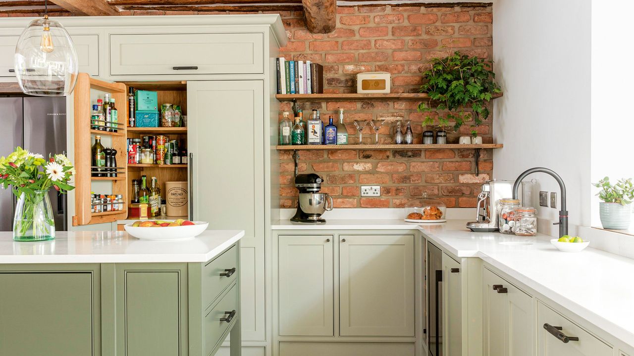 kitchen with exposed brick walls and two toned green cabinetry sandstone flooring