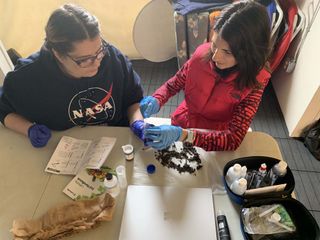Officers Monica Parks and Lori Waters test the properties of the simulated lunar volcanic regolith by HI-SEAS.