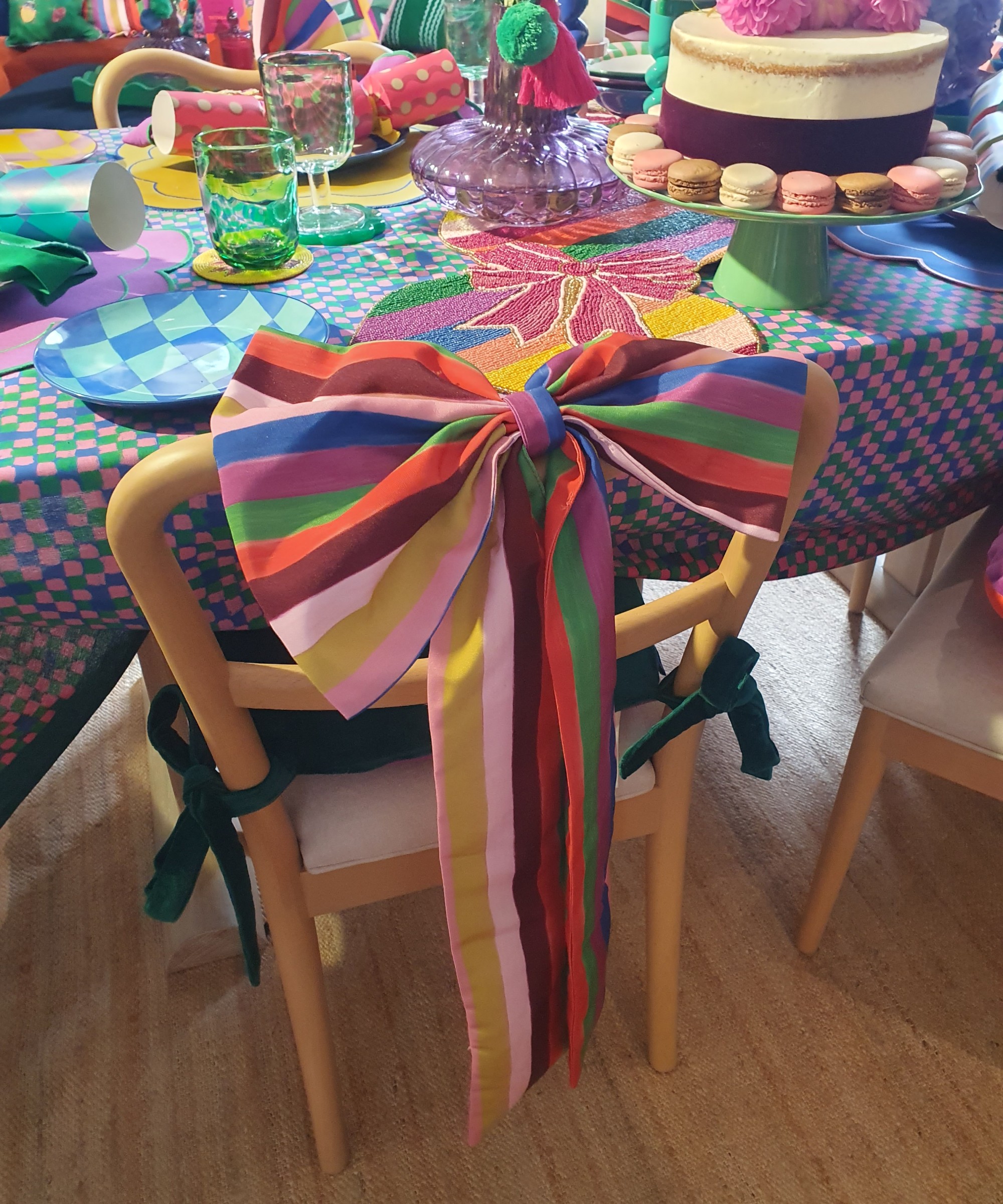 A dining table with chairs decorated with large striped bows from the Dunelm x Sophie Robinson collaboration