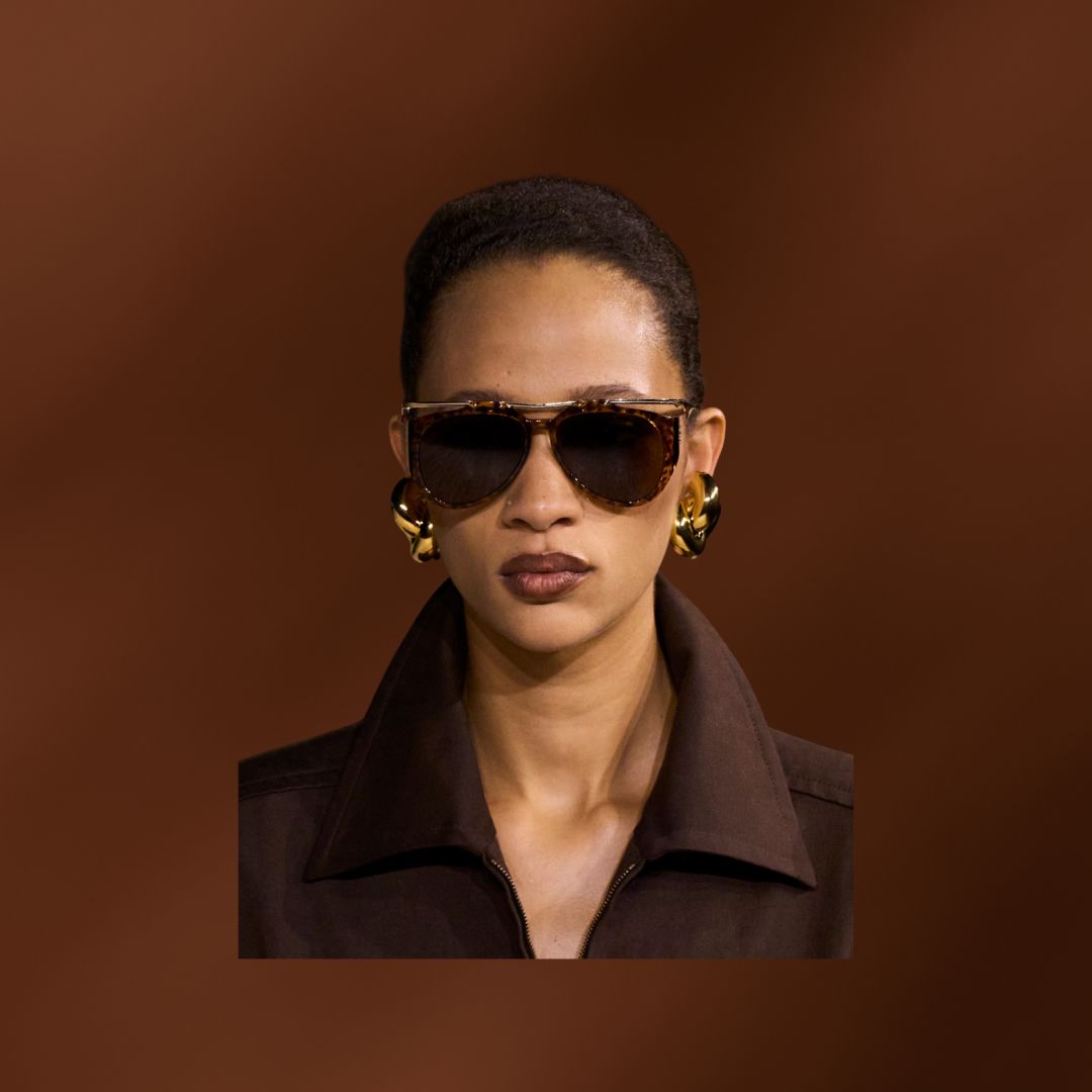 A models wearing brown lipstick and oversized brown sunglasses.