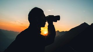 Man using binoculars at sunset