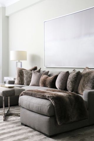Warm grey corner sofa with brown sheepskin throw draped over chaise