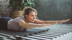 Woman lying on her front on a yoga mat with her head lifted and arms extended in front of her