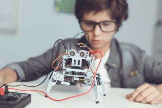 Boy in background controlling robot in foreground