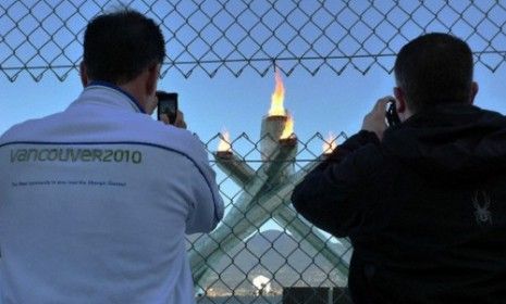 Views of Olympic cauldron are marred by a large chain-link fence.