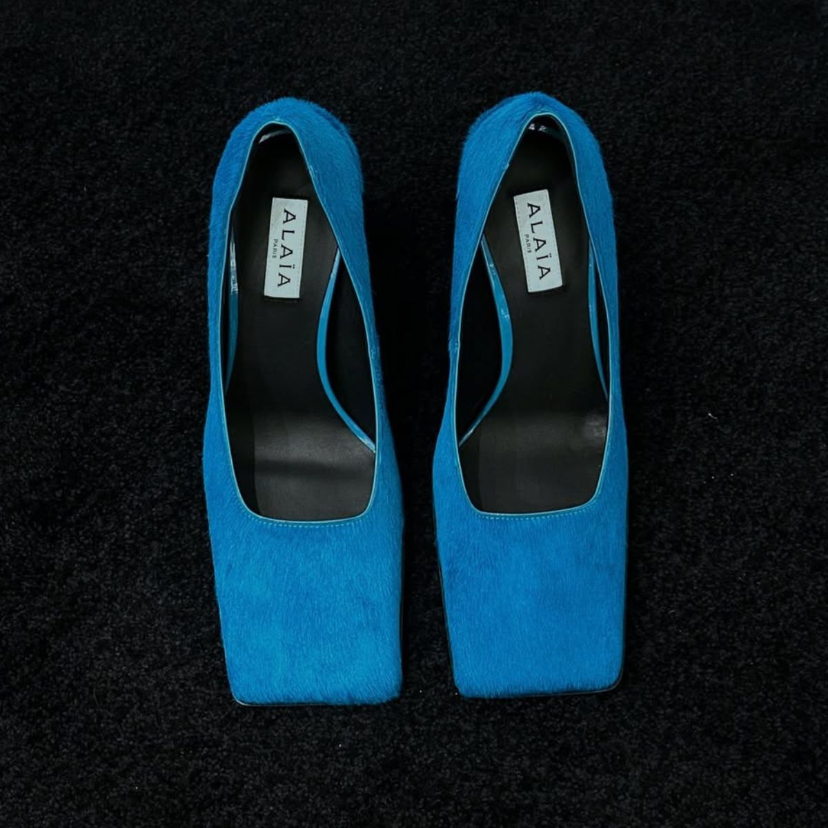 a close up of a pair of blue alaia square toe heels