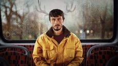 A promotional image for Netflix's Baby Reindeer, which shows Ricard Gadd sitting on the back seat of a bus