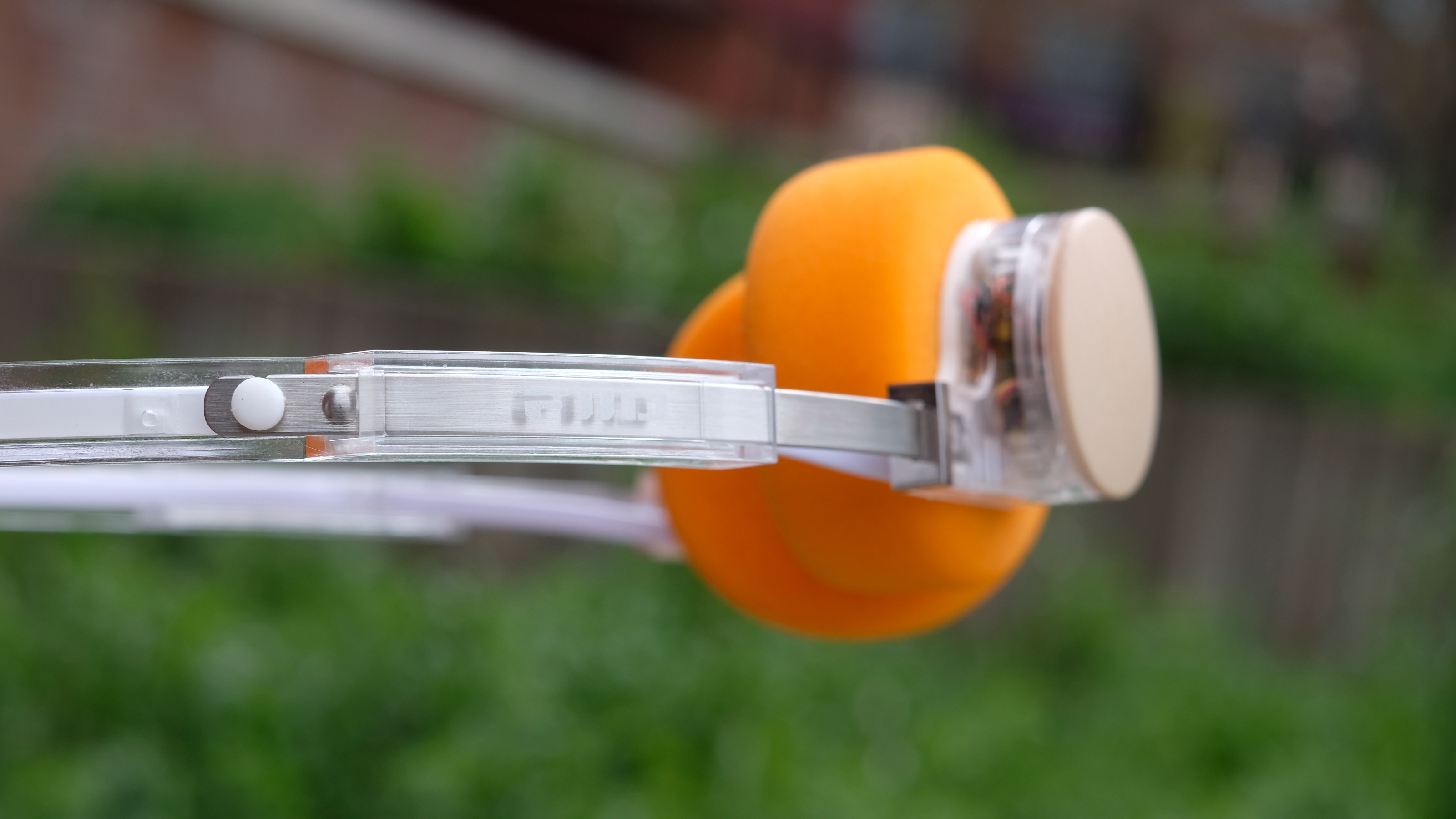 A photograph of the FiiO EH11 over-ear headphones with a transparent frame and orange foam earpads.