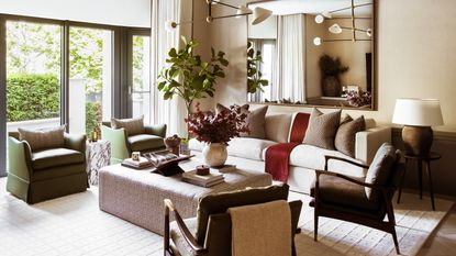 A living room with neutral walls, white sofa, and details in brown wood, green and rust red