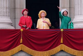 Queen Elizabeth in a coral coat and hat, The Queen Mother in a yellow coat and matching hat and Princess Margaret in a green coat and white hat waving from the balcony of Buckingham Palace in 1995