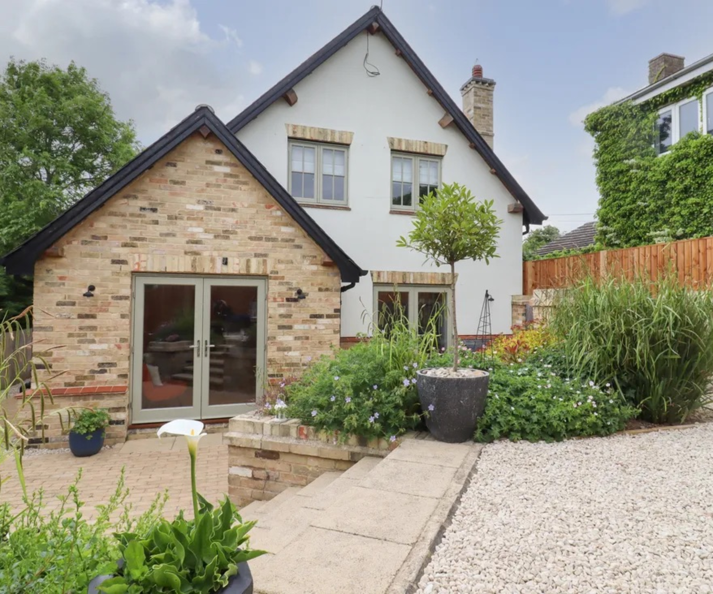 house with 2 pitched roof gable ends, side by side, one single storey finished in brick, the other double storey and rendered