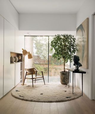 A neutral-toned room with large windows, a circular rug and seating
