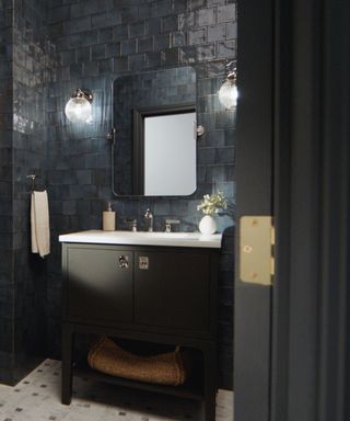 A blue tiled bathroom with a dark gray vanity