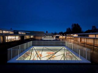 A dark sky view of school building with central underground space with glass light well.