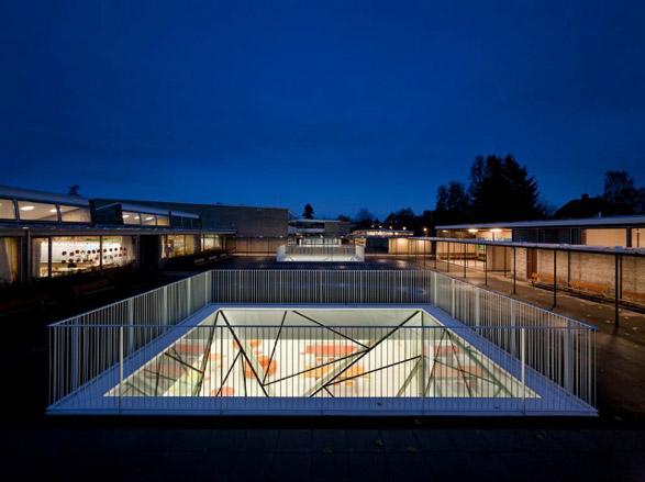 A dark sky view of school building with central underground space with glass light well.