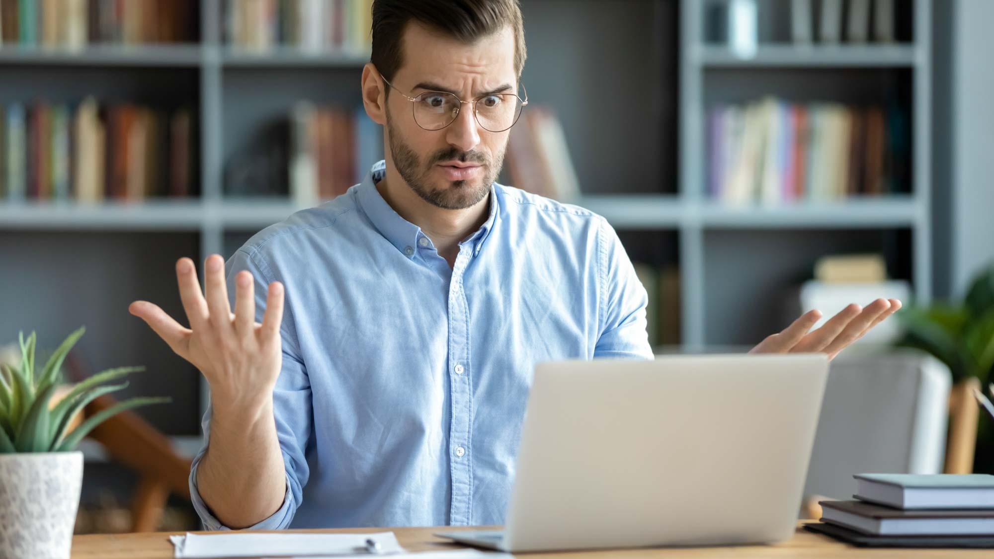 Man looking at his computer in disbelief due to internet problems