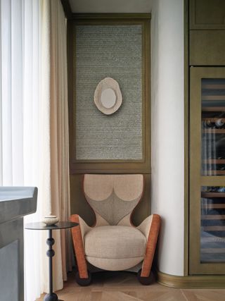 Corner of a room with olive green painted woodwork and neutral armchair
