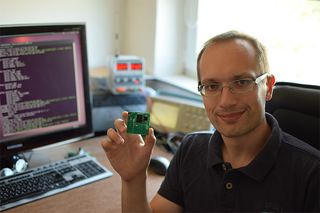 Electronics engineer Gediminas Strazdas holding a partially populated ThumbSat circuit board.